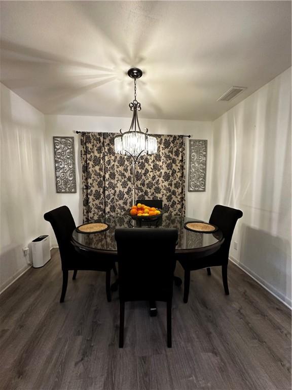 dining area featuring dark wood-type flooring, visible vents, and an inviting chandelier