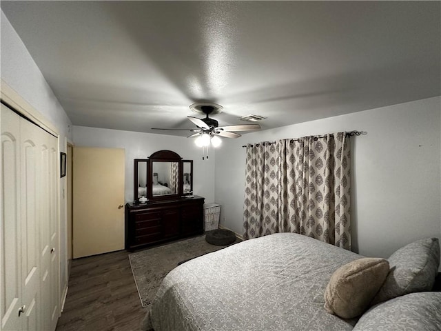 bedroom featuring a closet, dark wood-style flooring, visible vents, and a ceiling fan