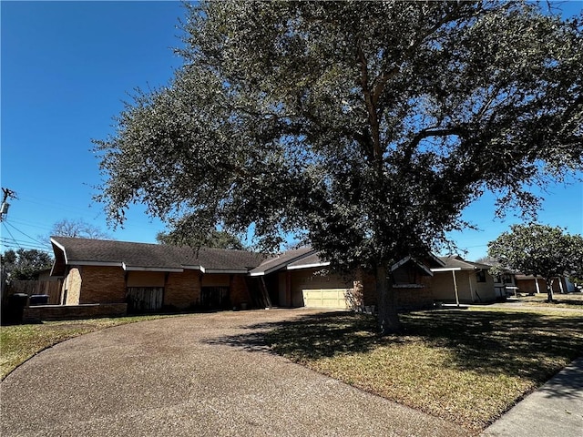 ranch-style home featuring a garage, a front yard, brick siding, and driveway