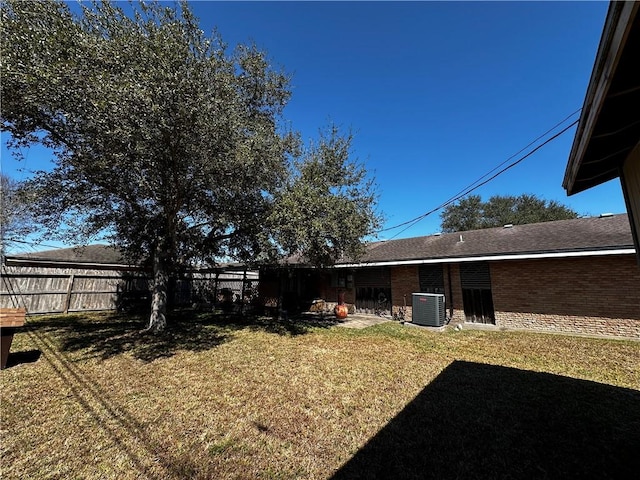 view of yard featuring fence and central AC