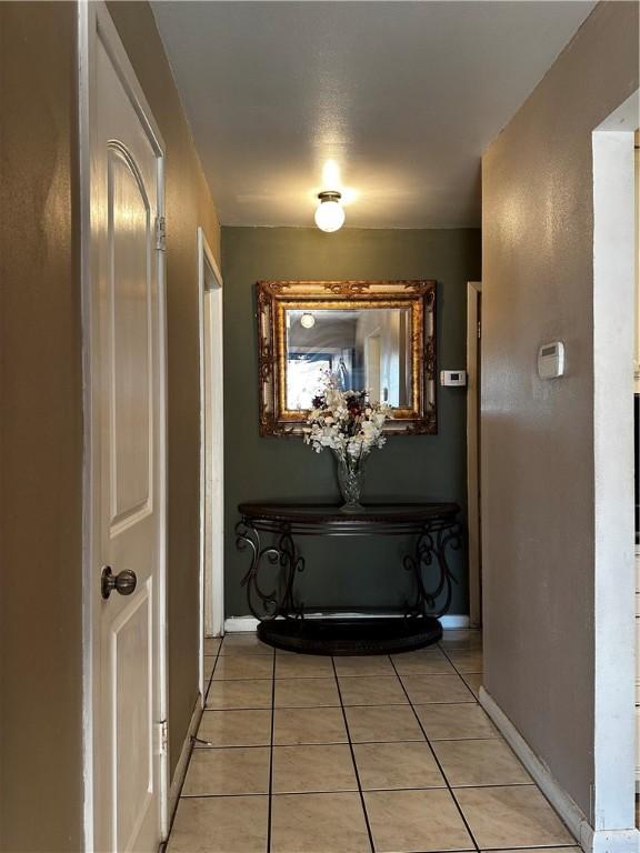 corridor featuring baseboards and light tile patterned floors