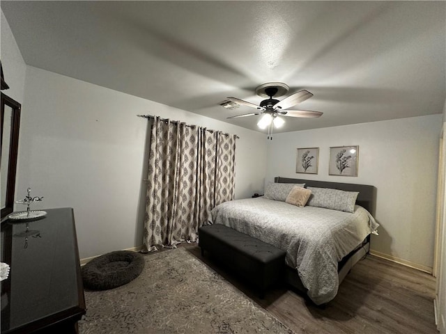 bedroom with a ceiling fan, baseboards, visible vents, and wood finished floors