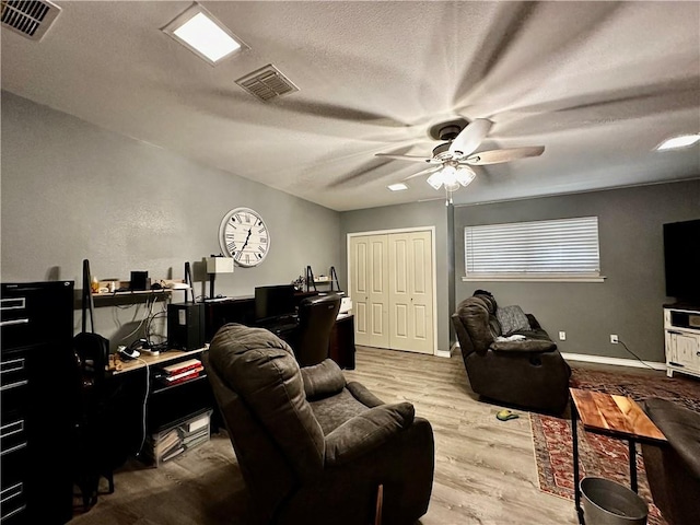 living area featuring visible vents, ceiling fan, a textured ceiling, and light wood finished floors