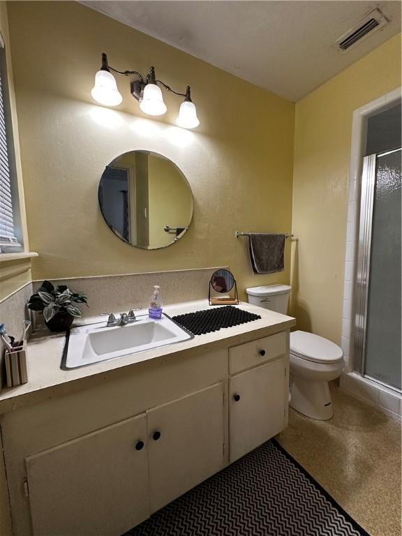 bathroom featuring toilet, a shower stall, visible vents, and vanity