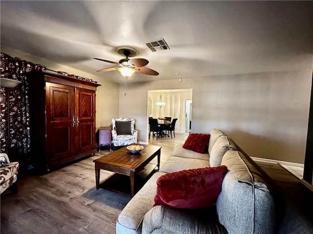 living room with light wood-style flooring, visible vents, and a ceiling fan