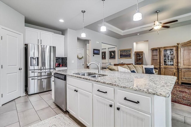 kitchen with white cabinets, appliances with stainless steel finishes, a kitchen island with sink, and sink