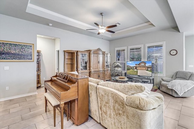 living room featuring light tile patterned floors, a tray ceiling, ceiling fan, and ornamental molding