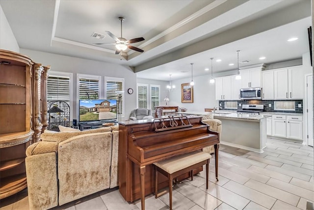 interior space featuring ceiling fan with notable chandelier, sink, and a tray ceiling