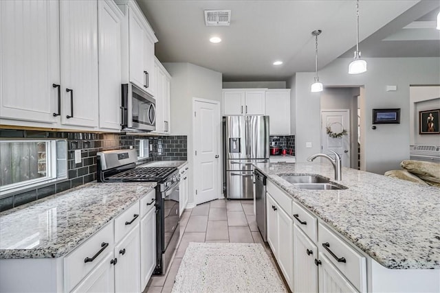 kitchen with a center island with sink, white cabinets, hanging light fixtures, and appliances with stainless steel finishes