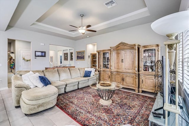 tiled living room with a raised ceiling, ceiling fan, and ornamental molding