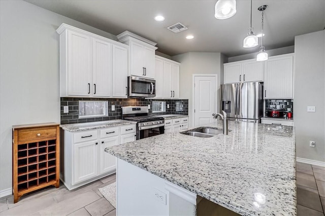 kitchen featuring pendant lighting, white cabinetry, stainless steel appliances, and an island with sink