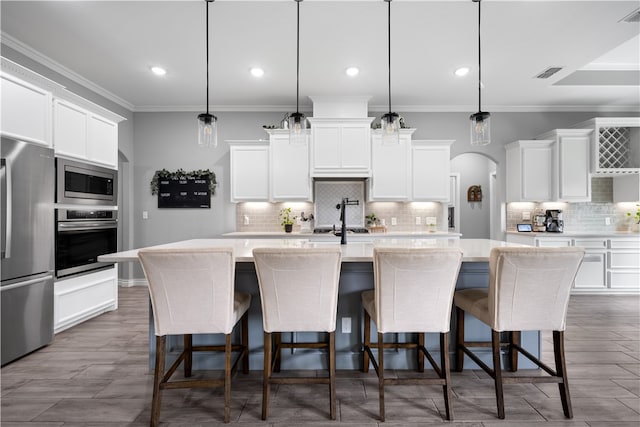 kitchen featuring pendant lighting, appliances with stainless steel finishes, and an island with sink