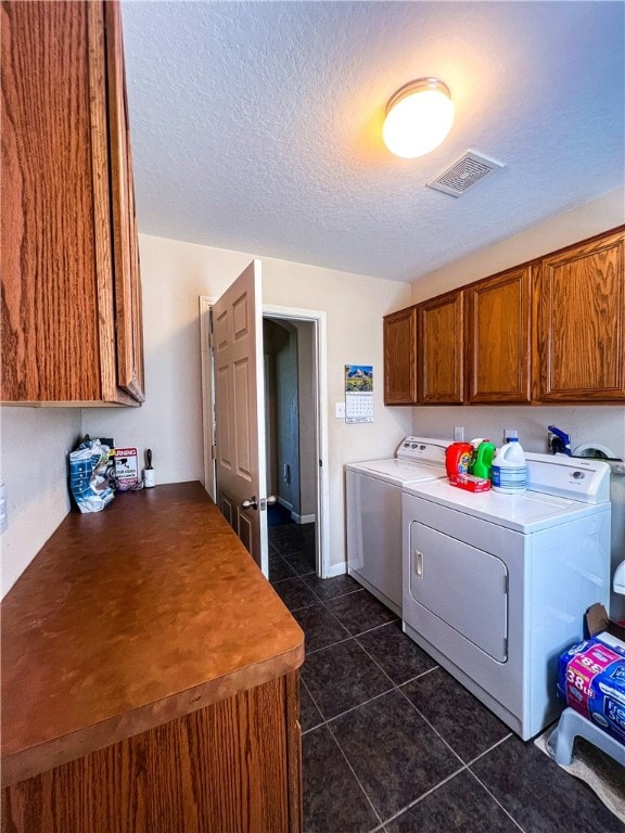 laundry room with cabinets, independent washer and dryer, a textured ceiling, and dark tile patterned flooring