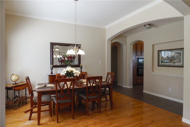 dining room featuring an inviting chandelier, ornamental molding, and hardwood / wood-style flooring