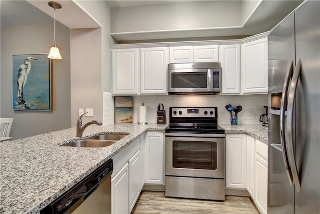 kitchen featuring white cabinetry, sink, hanging light fixtures, stainless steel appliances, and light hardwood / wood-style flooring