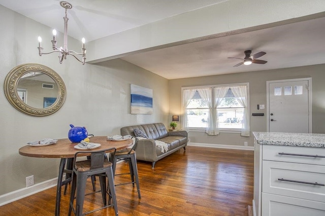 living room featuring ceiling fan with notable chandelier and dark wood-type flooring