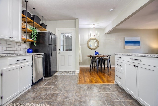 kitchen featuring backsplash, white cabinets, dishwasher, and a notable chandelier