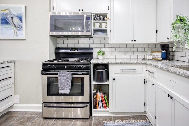 kitchen featuring light stone counters, appliances with stainless steel finishes, decorative backsplash, and white cabinetry