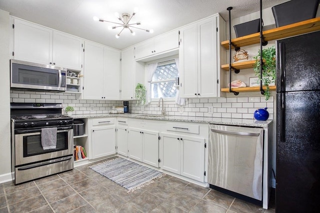 kitchen featuring sink, white cabinetry, light stone counters, and appliances with stainless steel finishes