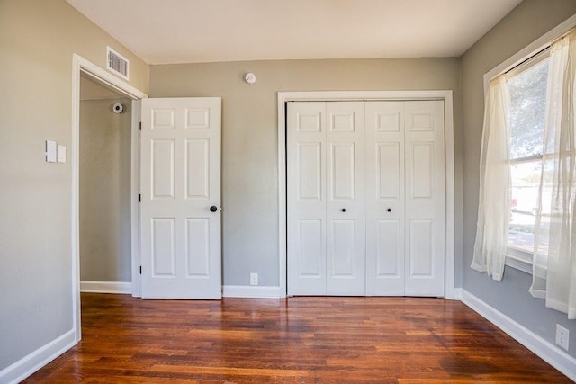 unfurnished bedroom featuring dark hardwood / wood-style flooring and a closet