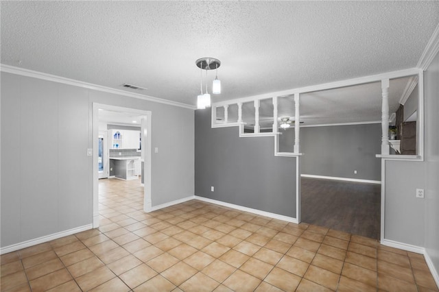 unfurnished room featuring visible vents, a textured ceiling, ornamental molding, and tile patterned flooring