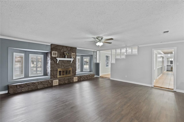 unfurnished living room featuring wood finished floors, visible vents, a fireplace, ceiling fan, and crown molding