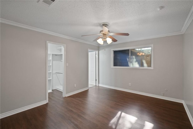 interior space with visible vents, a walk in closet, ornamental molding, wood finished floors, and baseboards