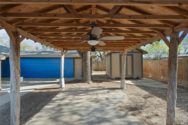 view of patio / terrace with a shed, a ceiling fan, an outdoor structure, and fence