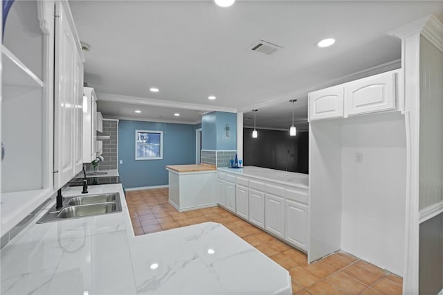 kitchen with light tile patterned floors, visible vents, a peninsula, a sink, and white cabinetry