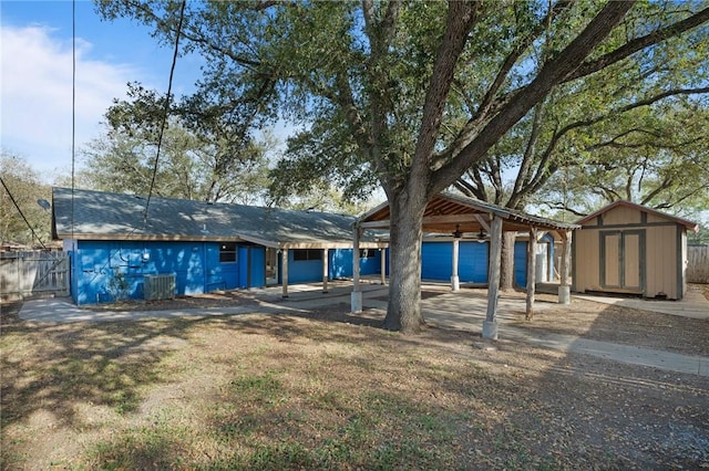 rear view of property with fence, a storage shed, an outbuilding, a ceiling fan, and a patio