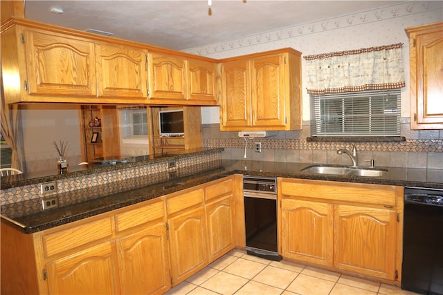 kitchen with light tile patterned flooring, black dishwasher, dark stone counters, and sink