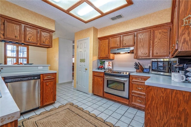 14613 Powell Dr, Corpus Christi, TX 78410 - kitchen featuring stainless steel appliances, under cabinet range hood, light countertops, brown cabinets, and a textured ceiling