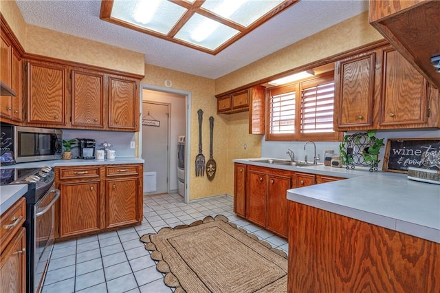 14613 Powell Dr, Corpus Christi, TX 78410 - kitchen featuring stainless steel appliances, light countertops, brown cabinets, light tile patterned floors, and a textured ceiling