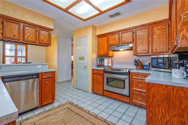 14613 Powell Dr, Corpus Christi, TX 78410 - kitchen with stainless steel appliances, under cabinet range hood, light countertops, brown cabinets, and a textured ceiling