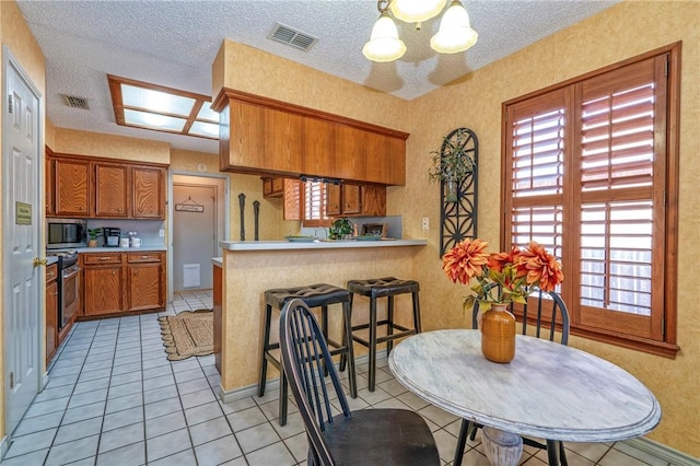 14613 Powell Dr, Corpus Christi, TX 78410 - kitchen with appliances with stainless steel finishes, brown cabinets, a peninsula, light countertops, and a chandelier