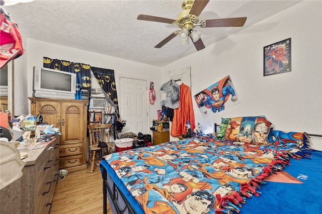 bedroom with a textured ceiling, light wood-type flooring, and ceiling fan