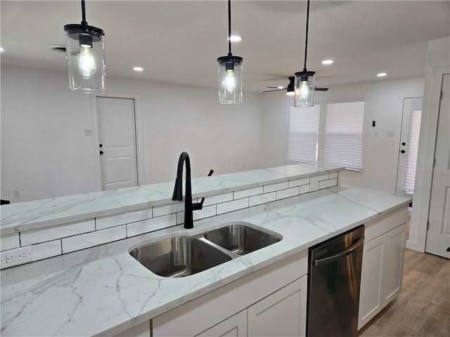 kitchen featuring black dishwasher, sink, white cabinets, and decorative light fixtures