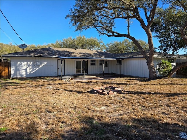 rear view of property with a patio, a lawn, and a fire pit