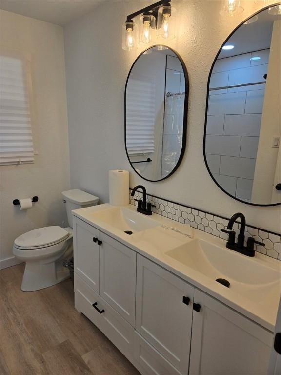 bathroom with walk in shower, toilet, vanity, hardwood / wood-style flooring, and decorative backsplash