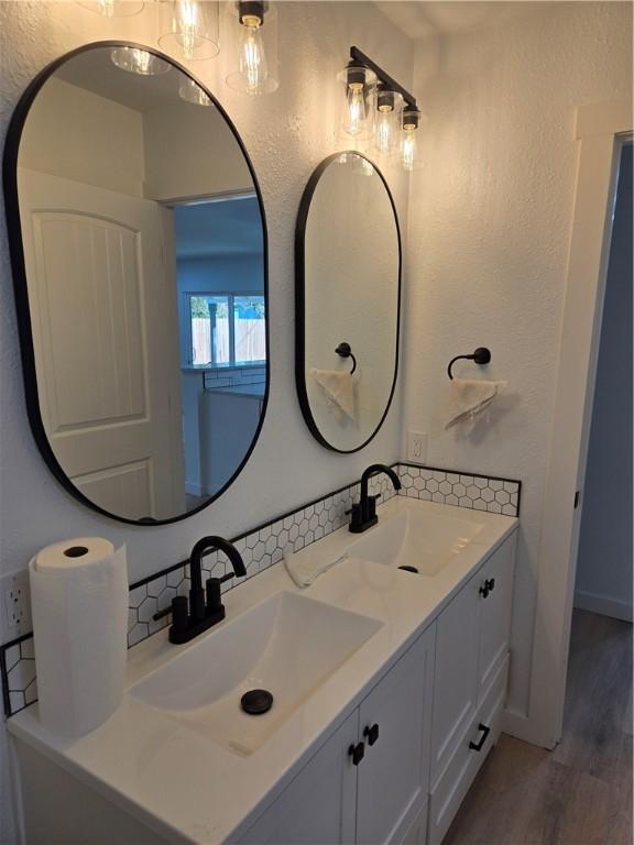 bathroom with vanity, wood-type flooring, and decorative backsplash