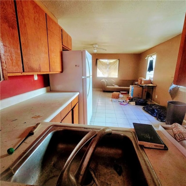 kitchen featuring light countertops, light tile patterned floors, a ceiling fan, and freestanding refrigerator