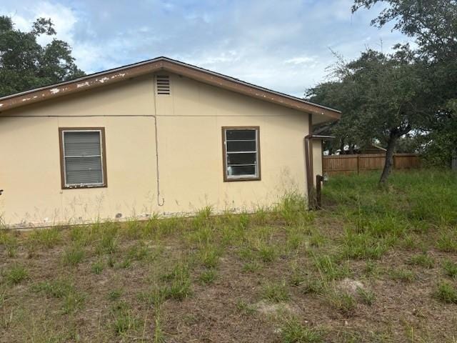 view of home's exterior with stucco siding and fence