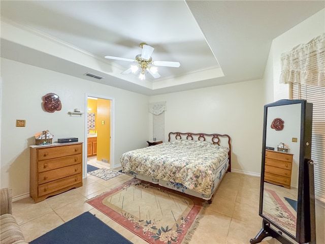 tiled bedroom featuring a tray ceiling, crown molding, ceiling fan, and ensuite bathroom