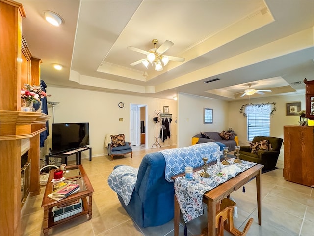 tiled living room with ornamental molding, ceiling fan, and a raised ceiling