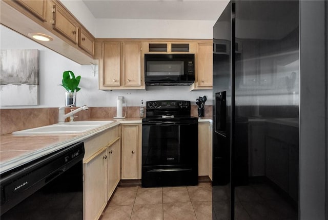 kitchen with light tile patterned flooring, sink, light brown cabinetry, and black appliances