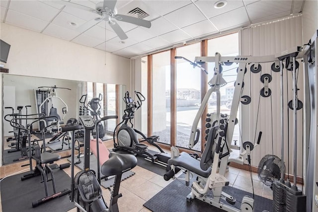 exercise room featuring ceiling fan, a wall of windows, a paneled ceiling, and a wealth of natural light