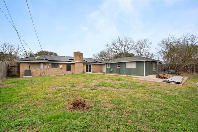 1318 W Cherrystone Dr, Corpus Christi, TX 78412 - back of house featuring a fenced backyard, brick siding, roof mounted solar panels, a chimney, and a patio area