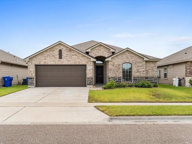 7717 Pruet Dr, Corpus Christi, TX 78414 - french country style house featuring brick siding, a garage, concrete driveway, and a front yard