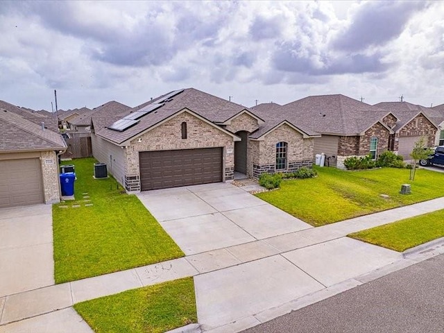7717 Pruet Dr, Corpus Christi, TX 78414 - view of front of house featuring brick siding, concrete driveway, an attached garage, roof mounted solar panels, and roof with shingles
