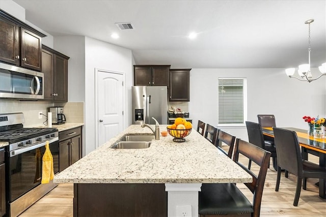 2673 Abbey Rd, Corpus Christi, TX 78415 - kitchen with appliances with stainless steel finishes, a sink, light wood-style floors, dark brown cabinets, and a breakfast bar